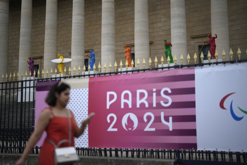 A woman walks past copies of one of the most famous Greek statues, the Venus of Milo, installed on the steps of the French National Assembly, Wednesday, July 3, 2024 in Paris. The statues by artist Laurent Perbos, have regained her arms and are now equipped with the attributes of six sporting disciplines. Just three weeks before the Olympics, the excitement that was building up in the host city has mingled with anxiety about France’s political future. (AP Photo/Thibault Camus)