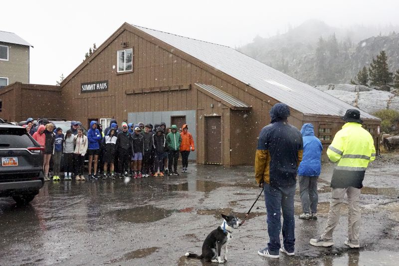 A group of cross country athletes, who had traveled from Davis, Calif., huddle after their practice was canceled due to wet and snowy conditions Saturday, Aug. 24, 2024, in Donner Summit, Calif. (AP Photo/Brooke Hess-Homeier)