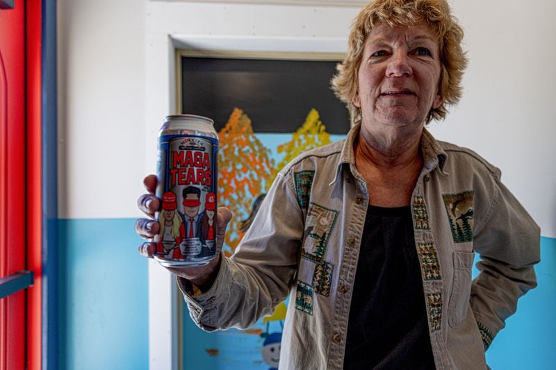 Customer Sue Brisk holds up a “MAGA Tears IPA: Their Frustration Brewed for Your Inebriation” beer at the Minocqua Brewing Company on Friday, June 7, 2024. (Photo by Donovan Johnson/News21)