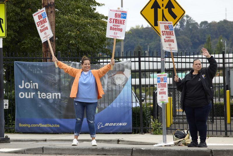 Boeing Machinists Union members Gina Forbush, left, and Tara Hays stand on a corner with a recruitment banner behind while on the picket line at the Renton afactory, Saturday, Sept. 14, 2024, in Renton, Wash. (AP Photo/John Froschauer)