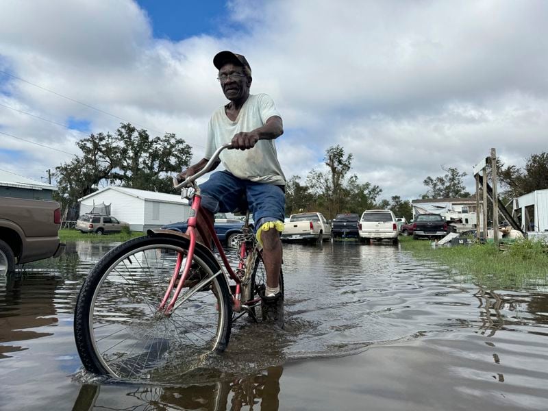 Carter Caldwell bikes through his family's flooded property just south of Houma, La. after Hurricane Francine tore through the area, Thursday, Sept. 12, 2024. (AP Photo/Jack Brook)