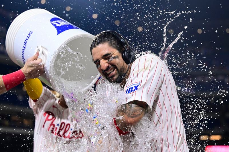 Philadelphia Phillies' Nick Castellanos is doused by teammates Brandon Marsh and Bryson Stott after hitting a walk off single against Atlanta Braves' Grant Holmes during the 11th inning of a baseball game, Sunday, Sept. 1, 2024, in Philadelphia. (AP Photo/Derik Hamilton)