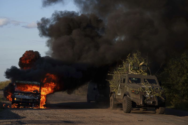 A Ukrainian armoured military vehicle travels past a burned car near the Russian-Ukrainian border, Sumy region, Ukraine, Wednesday, Aug. 14, 2024. (AP Photo/Evgeniy Maloletka)