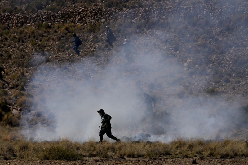 A government supporter runs through tear gas during clashes with supporters of former President Evo Morales who are marching to the capital to protest the government of current President Luis Arce in Vila Vila, Bolivia, Tuesday, Sept. 17, 2024. (AP Photo/Juan Karita)