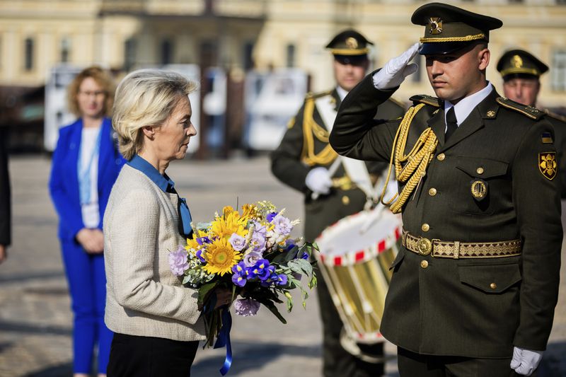 President of the European Commission Ursula von der Leyen, left, holds a bouquet of flowers to place at a wall commemorating the fallen Ukrainian soldiers in the war with Russia, in Kyiv, Ukraine, Friday, Sept. 20, 2024. (Christoph Soeder, Pool via AP)