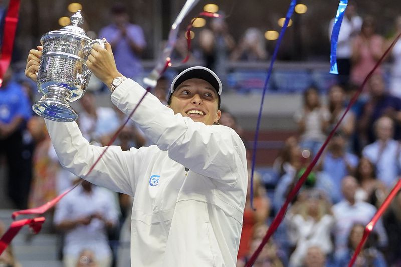 FILE - Iga Swiatek, of Poland, holds up the championship trophy after defeating Ons Jabeur, of Tunisia, to win the women's singles final of the U.S. Open tennis championships, Saturday, Sept. 10, 2022, in New York. (AP Photo/Frank Franklin II, File)