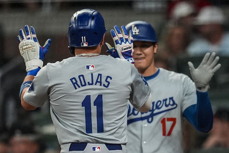 Los Angeles Dodgers' Miguel Rojas (11) celebrates his solo homer with Shohei Ohtani (17) in the third inning of a baseball game against the Atlanta Braves, Friday, Sept. 13, 2024, in Atlanta. (AP Photo/Mike Stewart)