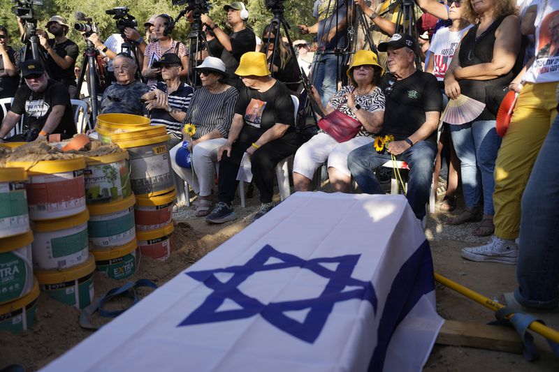 Mourners wait for the funeral for slain hostage Avraham Munder, who was killed in Hamas captivity in the Gaza Strip, at Kibbutz Nir Oz, southern Israel, Wednesday, Aug. 21, 2024. On Tuesday, the Israeli military said its forces recovered six bodies of hostages kidnapped on Oct. 7, 2023 in an overnight operation in southern Gaza. (AP Photo/Ohad Zwigenberg)