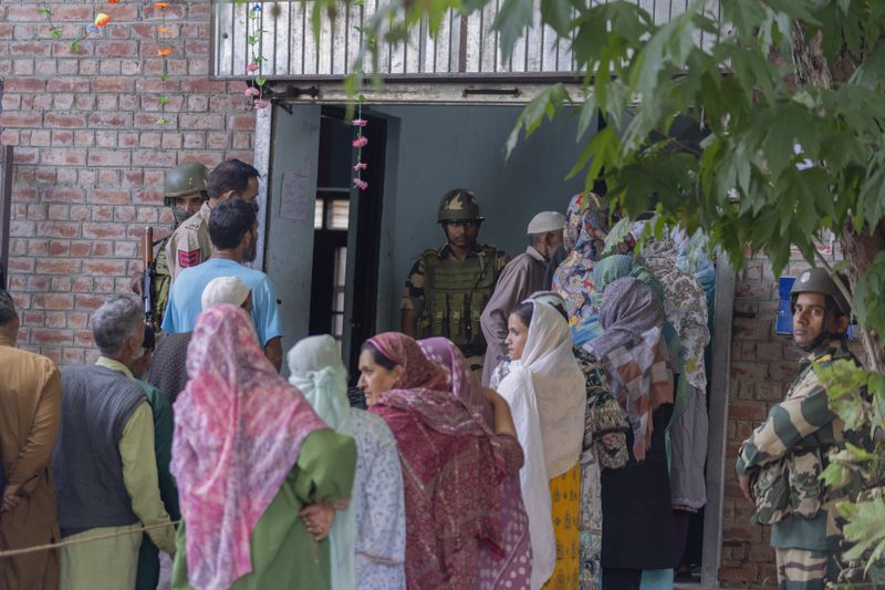 Indian paramilitary soldiers stand guard as people queue up at a polling booth to cast their vote in Naira, south of Srinagar, Indian controlled Kashmir, Wednesday, Sept. 18, 2024. (AP Photo/Dar Yasin)