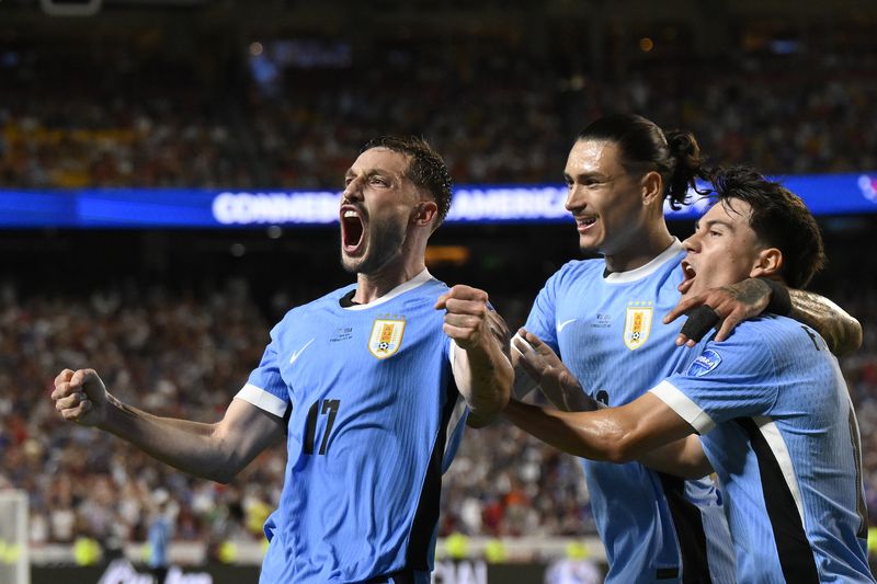 Uruguay's Matias Vina, left, celebrates his side's opening goal against United States scored by teammate Mathias Olivera during a Copa America Group C soccer match in Kansas City, Mo., Monday, July 1, 2024. (AP Photo/Reed Hoffman)