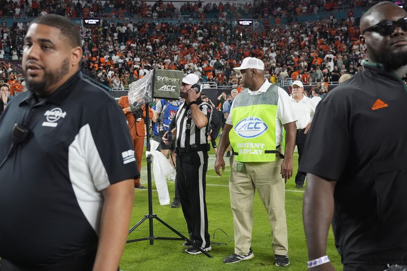 An NCAA official reviews a play at the end of the last second of an NCAA college football game, Friday, Sept. 27, 2024, in Miami Gardens, Fla. The play was first ruled a touchdown and then after a lengthy review it was reversed to an incomplete pass. (AP Photo/Marta Lavandier)