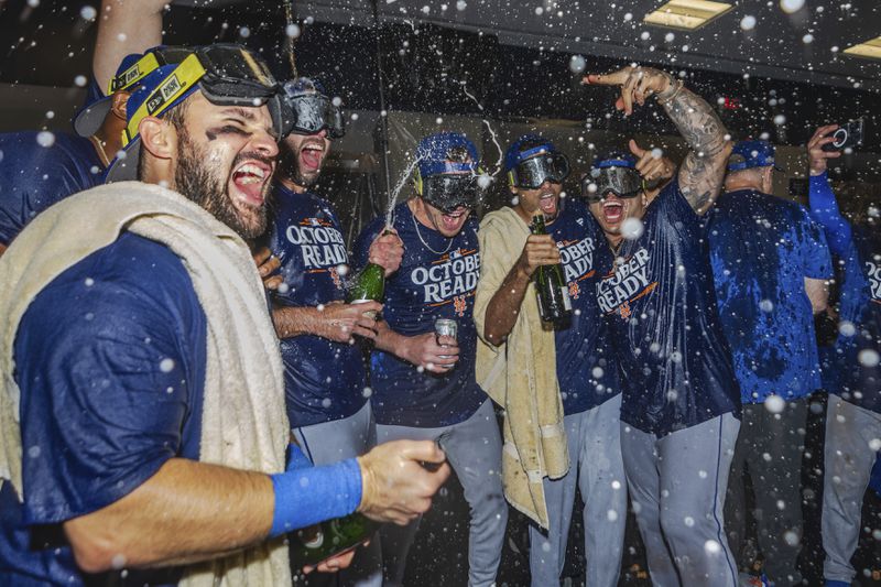 The New York Mets celebrate in the locker room after clinching a wild-card playoff berth after the second baseball game of a doubleheader against the Atlanta Braves, Monday, Sept. 30, 2024, in Atlanta. (AP Photo/Jason Allen)