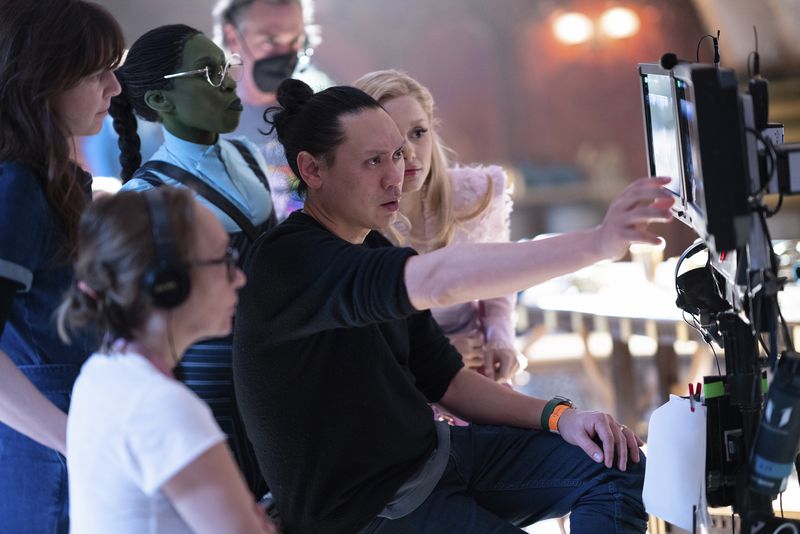 This image released by Universal Pictures shows director Jon M. Chu, center, on the set of "Wicked." (Giles Keyte/Universal Pictures via AP)