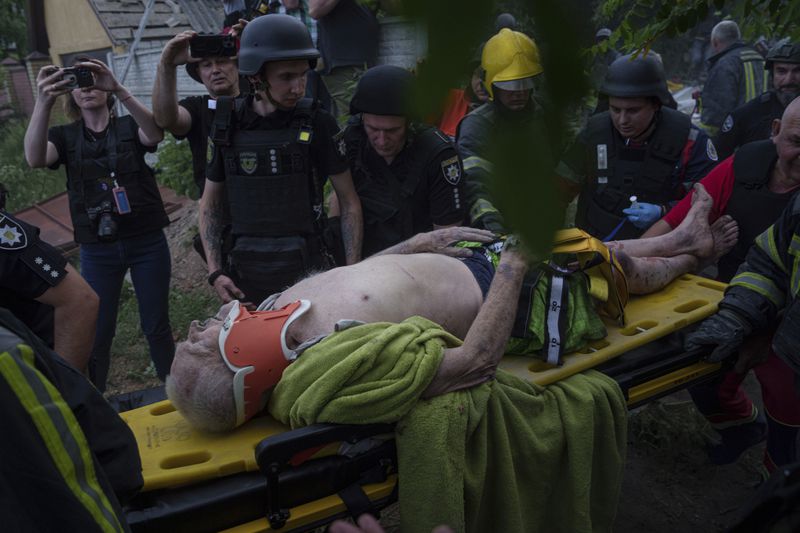 Rescue workers and police officers carry an injured person by a stretcher to an ambulance from a building which was destroyed by a Russian airstrike in Kharkiv, Ukraine, Monday, June 10, 2024. (AP Photo/Evgeniy Maloletka)