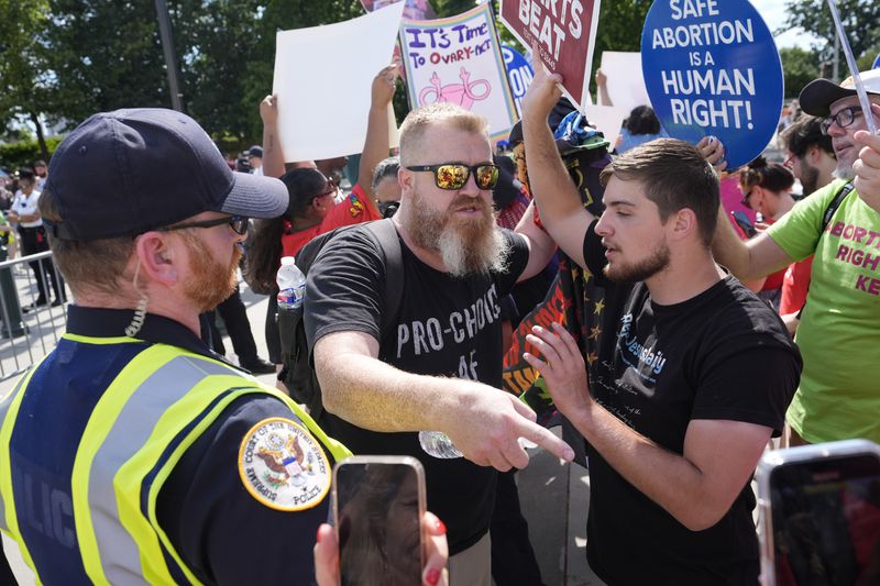 A Supreme Court police officer monitors the scene as abortion rights activists and Women's March leaders clash with anti-abortion counter-protesters during a national day of strike actions outside the Supreme Court, Monday, June 24, 2024, in Washington. (AP Photo/Alex Brandon)