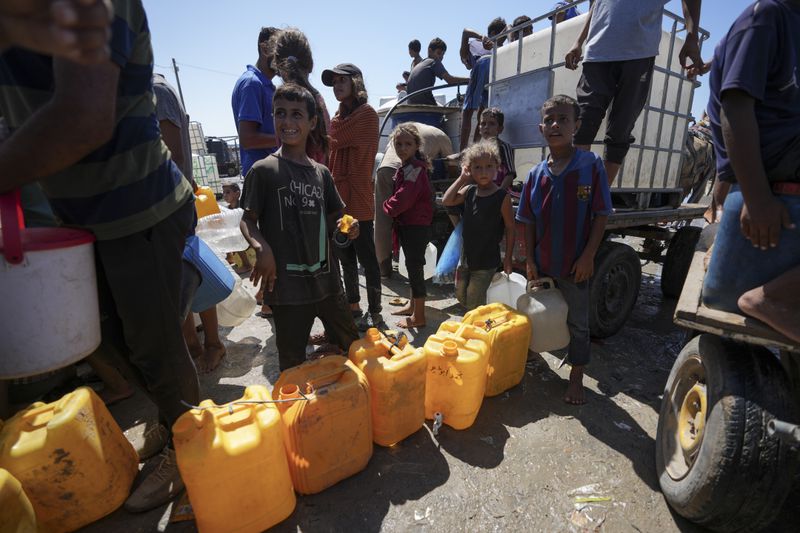 Displaced Palestinians line up to collect water, in Deir al Balah, central Gaza Strip, Friday, Aug. 23, 2024. (AP Photo/Abdel Kareem Hana)