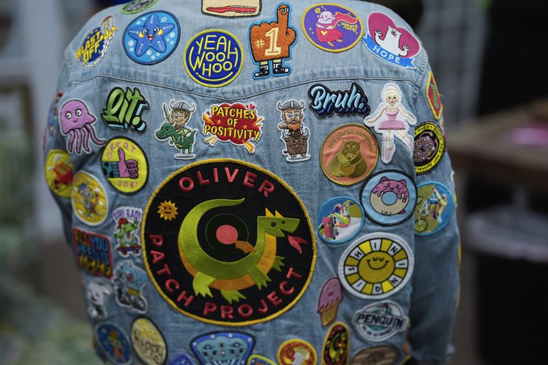 Brian Burkhardt, who runs the Oliver Patch Project which the family started after seeing how much donated patches boosted the morale of son Oliver when he underwent cancer treatment at age 9, wears a jacket covered with patches inside the charity's office, Wednesday, Sept. 4, 2024, in Miami. (AP Photo/Rebecca Blackwell)