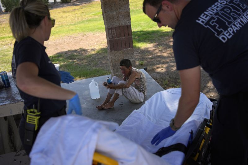 Members of the Henderson Fire Department prepare to take Deb Billet, 66, to the hospital for heat-related symptoms, Wednesday, July 10, 2024, in Henderson, Nev. Billet has been living on the street. (AP Photo/John Locher)