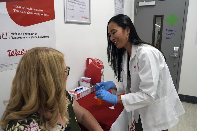 Anh Nguyen prepares to administer a COVID-19 vaccine for Kelly Vazquez at a pharmacy in New York, Tuesday, Sept. 24, 2024. (AP Photo/Mary Conlon)