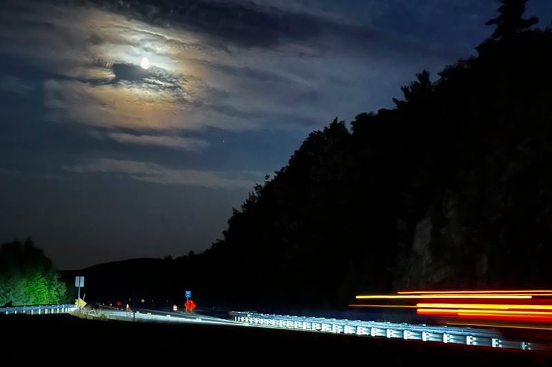 In this long exposure photo, a ring forms around the moon as cars drive along Mt. Major Highway near Lake Winnipesaukee in Alton Bay, N.H., Thursday, Sept. 12, 2024, as Canada and northern U.S. cities experience moderate solar storms. (AP Photo/Caleb Jones)