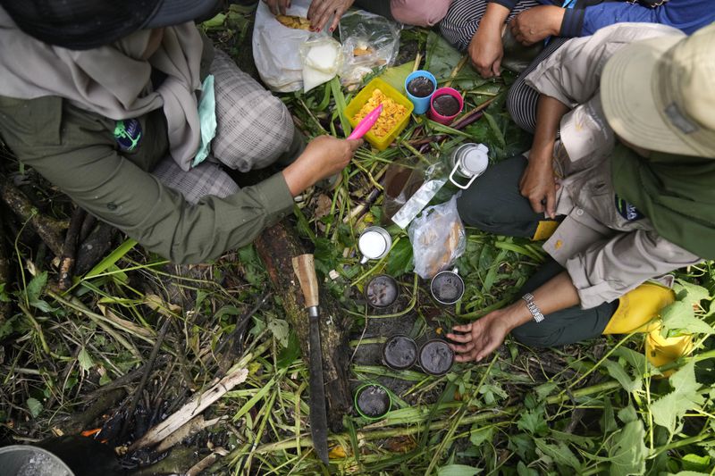 Rangers prepare snacks and coffee as they take a break during a forest patrol in Damaran Baru, Aceh province, Indonesia, Tuesday, May 7, 2024. The female-led group of forest rangers are defying social norms to lead patrols in the jungle to combat deforestation. (AP Photo/Dita Alangkara)