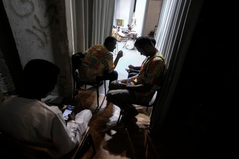 Sudanese Camirata troupe members chat with their families on mobile phones before their show at the Russian culture center in Cairo, Egypt, Sunday, Sept. 15, 2024. (AP Photo/Amr Nabil)