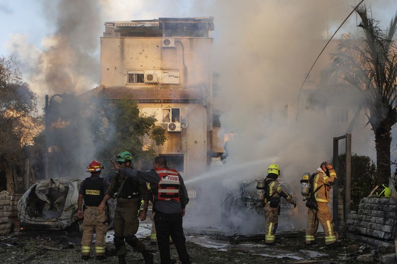 Israeli security and rescue forces work at the site hit by a rocket fired from Lebanon, in Kiryat Bialik, northern Israel, on Sunday, Sept. 22, 2024. (AP Photo/Gil Nechushtan)