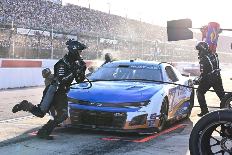 The pit crew for Carson Hocevar (77) rush to complete a pit stop during a NASCAR Cup Series auto race at Darlington Raceway, Sunday, Sept. 1, 2024, in Darlington, S.C. (AP Photo/Matt Kelley)