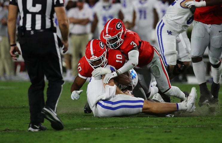 Georgia defenders Jamon Dumas-Johnson (10) and Kamari Lassiter sack Kentucky quarterback Devin Leary for a loss during the second quarter in a NCAA college football game on Saturday, Oct. 7, 2023, in Athens.  Curtis Compton for the Atlanta Journal Constitution