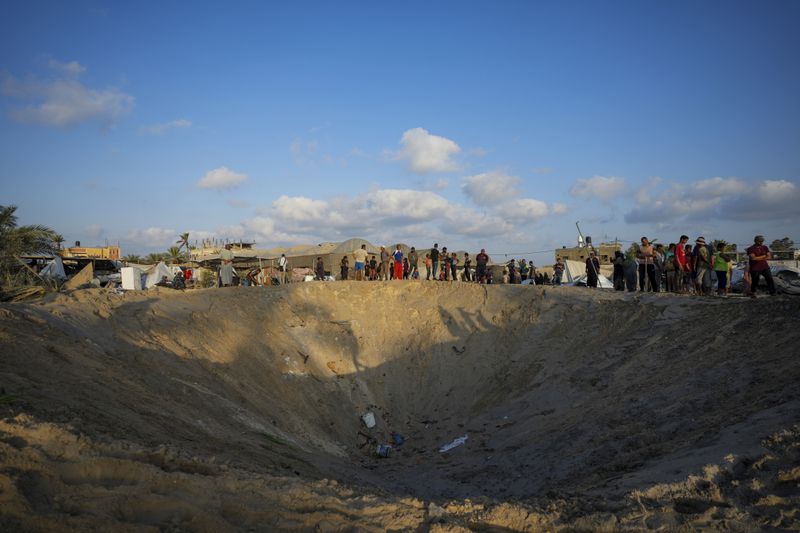 Palestinians look at the destruction after an Israeli airstrike on a crowded tent camp housing Palestinians displaced by the war in Muwasi, Gaza Strip, Tuesday, Sept. 10, 2024. An Israeli strike killed at least 40 people and wounded 60 others early Tuesday, Palestinian officials said. Israel said it targeted "significant" Hamas militants, allegations denied by the militant group. (AP Photo/Abdel Kareem Hana)