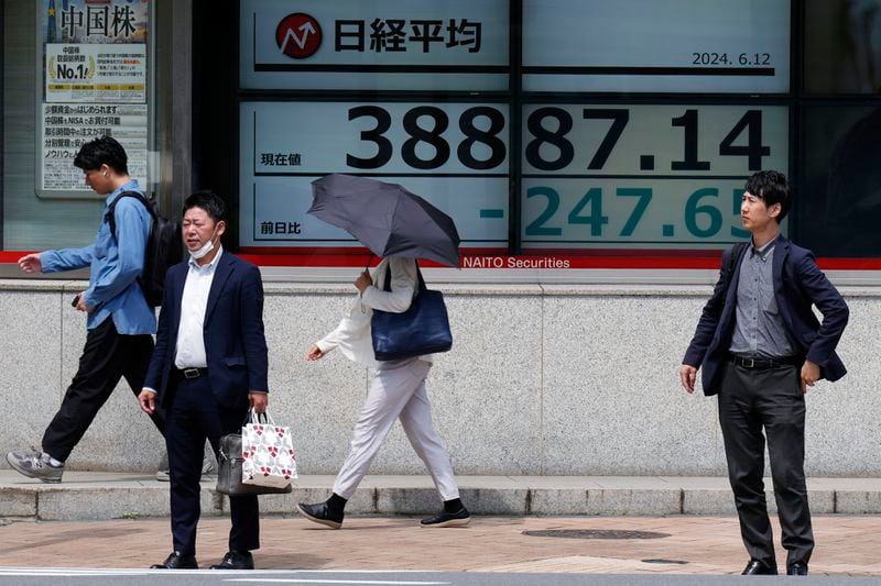 People stand in front of an electronic stock board showing Japan's Nikkei 225 index at a securities firm Wednesday, June 12, 2024, in Tokyo. (AP Photo/Eugene Hoshiko)