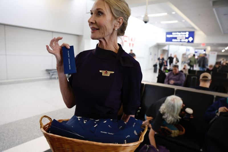 Delta Air Lines flight attendant Roxan Buslee passes out solar eclipse glasses to travelers Monday, April 8, 2024, at Dallas Fort Worth International Airport. (Natrice Miller/AJC)