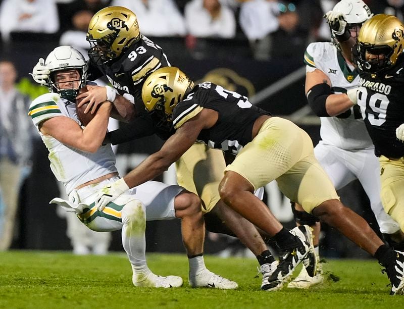 Baylor quarterback Sawyer Robertson, left, is stopped after a short gain by Colorado defensive ends Samuel Okunlola, back right, and BJ Green II in the second half of an NCAA college football game Saturday, Sept. 21, 2024, in Boulder, Colo. (AP Photo/David Zalubowski)