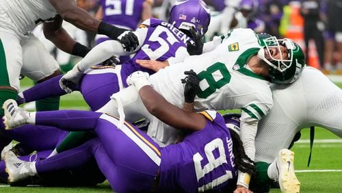 New York Jets quarterback Aaron Rodgers (8), right, reacts as he is tackled during the second half of an NFL football game against the Minnesota Vikings, Sunday, Oct. 6, 2024, at the Tottenham Hotspur stadium in London. (AP Photo/Kirsty Wigglesworth)