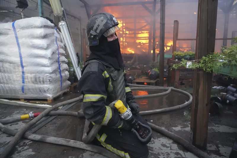 A firefighter puts out a fire after two guided bombs hit a large construction supplies store in Kharkiv, Ukraine, Saturday, May 25, 2024. (AP Photo/Andrii Marienko)