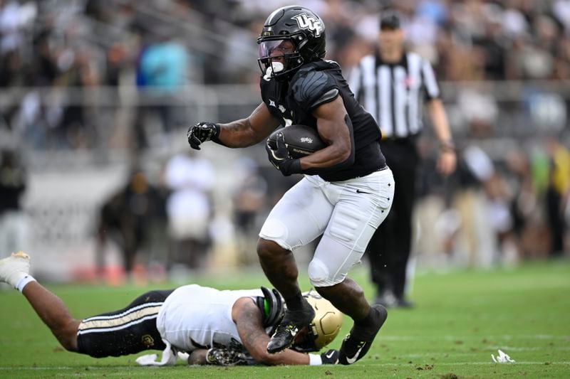 Central Florida running back RJ Harvey, front right, rushes for yardage as Colorado safety Cam'Ron Silmon-Craig, bottom, defends during the first half of an NCAA college football game, Saturday, Sept. 28, 2024, in Orlando, Fla. (AP Photo/Phelan M. Ebenhack)