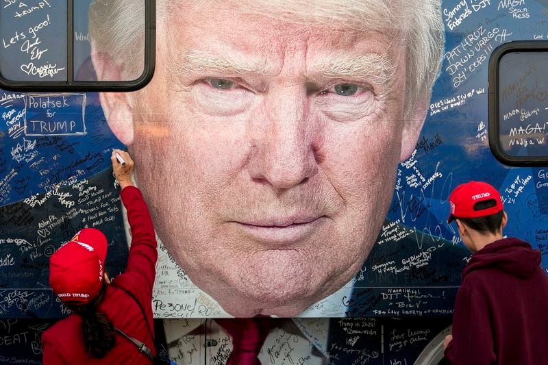 Supporters of Republican presidential nominee former President Donald Trump sign a bus before a campaign rally at the Butler Farm Show, Saturday, Oct. 5, 2024, in Butler, Pa. (AP Photo/Julia Demaree Nikhinson)