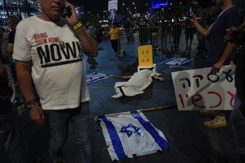 People take part in a performance during a protest against Israel Prime Minister Benjamin Netanyahu's government and call for the release of hostages held in the Gaza Strip by the Hamas militant group, in Tel Aviv, Israel, Saturday, Oct. 5, 2024. (AP Photo/Ariel Schalit)