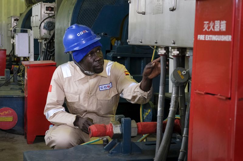 FILE - A Ugandan worker from China Oilfield Services Limited (COSL), a contractor for China National Offshore Oil Corporation (CNOOC), inspects pipes on the drilling rig at the Kingfisher oil field on the shores of Lake Albert in the Kikuube district of western Uganda Tuesday, Jan. 24, 2023. (AP Photo/Hajarah Nalwadda, File)