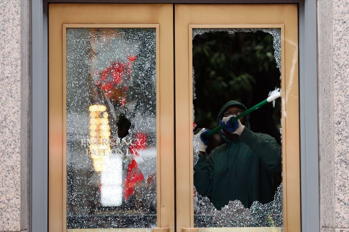 A person removes what is left of a broken window at 191 Peachtree Tower in Downtown Atlanta. The aftermath of last night's violent protests left damaged buildings and six Forest Defenders arrested. Sunday, January 22, 2023. Miguel Martinez / miguel.martinezjimenez@ajc.com