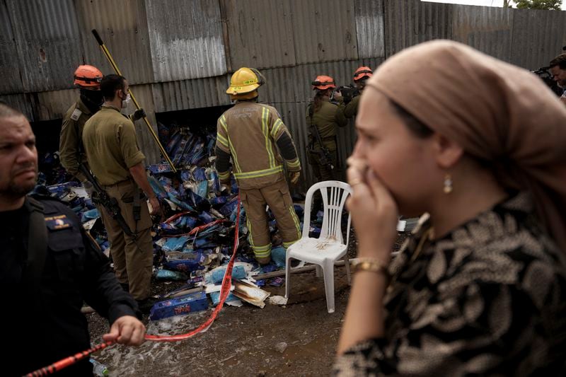 A woman reacts as emergency personnel respond after a rocket apparently fired from Gaza hits Kfar Chabad Tel Aviv, Monday, Oct. 7, 2024. (AP Photo/Oded Balilty)