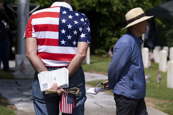 Jim Hickey, who served 27 years in the Army, holds programs and flags before the start of the Memorial Day ceremony at Marietta National Cemetery on Monday, May 27, 2024. (Ben Gray / Ben@BenGray.com)