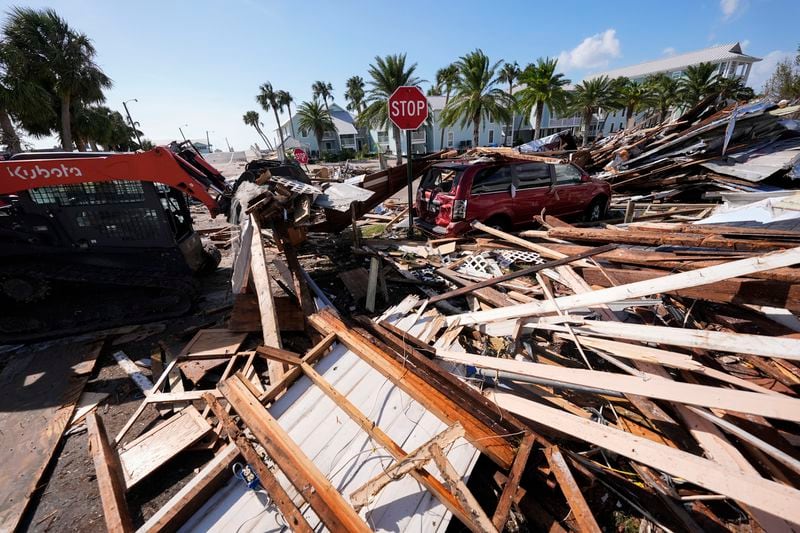 Workers clear debris in the aftermath of Hurricane Helene, in Cedar Key, Fla., Friday, Sept. 27, 2024. (AP Photo/Gerald Herbert)