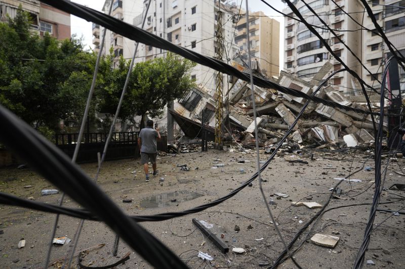 A man checks the damaged buildings at the site of an Israeli airstrike in Beirut's southern suburb, Lebanon, Tuesday, Oct. 1, 2024. (AP Photo/Hassan Ammar)