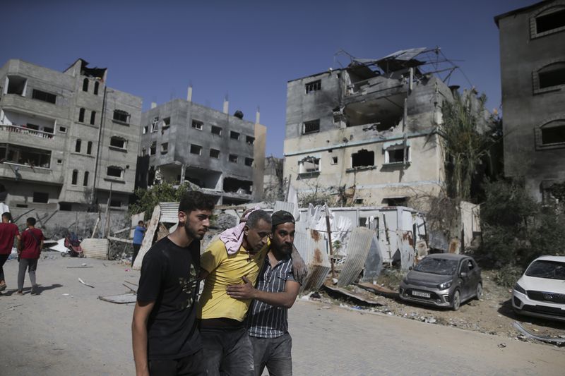 FILE - Palestinians help a wounded man after Israeli strikes in Nuseirat refugee camp, Gaza Strip, on June 8, 2024. The United Nations chief appealed for funding Friday, July 12, 2024, for the beleaguered U.N. agency helping Palestinian refugees in Gaza and elsewhere in the Middle East, accusing Israel of issuing evacuation orders in the war-torn territory forcing Palestinians “to move like human pinballs across a landscape of destruction and death.”(AP Photo/Jehad Alshrafi, File)