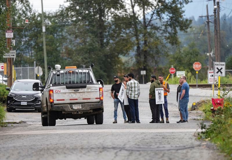 Employees in a pickup truck stop to talk to locked out Canadian National Rail workers standing at a picket line at CN Rail's Thornton Yard in Surrey, British Columbia, Canada, Thursday, Aug. 22, 2024. (Darryl Dyck/The Canadian Press via AP)