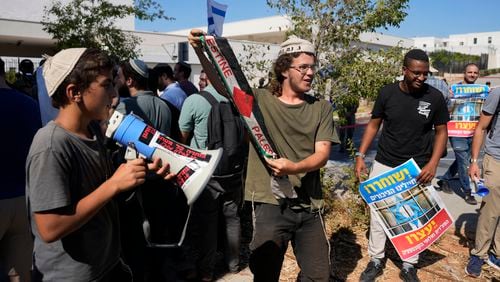 Right-wing Israelis, one holding a Palestinian scarf, at a protest outside of the initial hearing in military court for nine Israeli soldiers over what a defense lawyer said were allegations of sexual abuse of a Palestinian at a shadowy facility where Israel has held prisoners from Gaza during the war, in Beit Lid military base, Tuesday, July 30, 2024. (AP Photo/Ohad Zwigenberg)