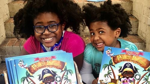 Selah Thompson, founder of The Empowered Readers Literacy Project with her little sister, Syrai, shown with the first book of Selah's "Penelope the Pirate Princess" series.