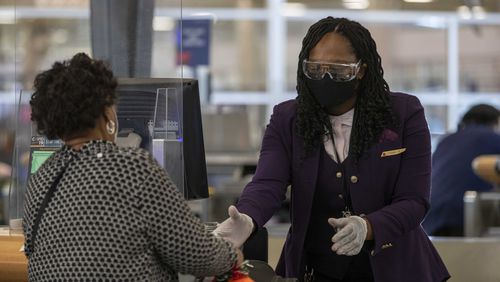 A Delta Air Lines employee handles a passenger's luggage while wearing goggle, gloves and face mask in the Domestic Terminal at Hartsfield-Jackson Atlanta International Airport in Atlanta , Monday, November 23, 2020.  (Alyssa Pointer / Alyssa.Pointer@ajc.com)