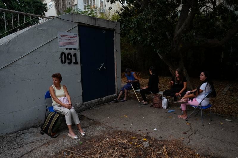 Israelis sit next to a public bomb shelter to stay safe from rockets fired from Lebanon, in Haifa, northern Israel, on Tuesday, Sept. 24, 2024. (AP Photo/Baz Ratner)